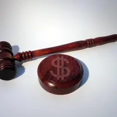 Młotek sędziowski i podstawa z symbolem dolara. Jak uniknąć kary od ubezpieczeniowego funduszu gwarancyjnego?