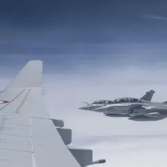 Dwa myśliwce Rafale, napędzane silnikami Safran, lecą w formacji nad chmurami. Widoczny fragment skrzydła samolotu z francuską kokardą.