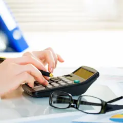 Dłonie na kalkulatorze, obok okulary i wykresy. Czy Vivus rozkłada na raty? Analiza finansowa.