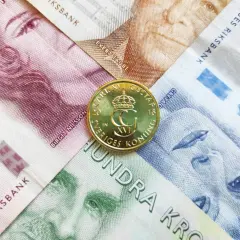 Szwedzka korona, czyli jaka waluta jest w Szwecji, widoczna na banknotach z portretami i złotej monecie z wizerunkiem króla Karola XVI Gustawa.