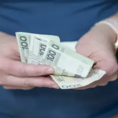 Dłonie trzymające banknoty 100 zł i 200 zł. Zastanawiasz się, o ile wzrośnie oprocentowanie lokat?
