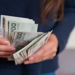 Dłonie trzymające plik banknotów 100 zł. Słowacja jaka waluta? Obecnie euro, ale kiedyś był to słowacki korona.