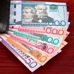 Dominikańskie pesos w różnych nominałach wychodzące z czarnego portfela.