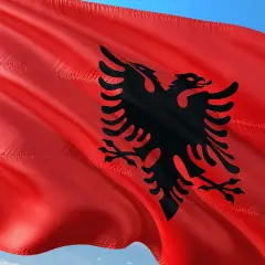 Czerwona flaga Albanii z czarnym dwugłowym orłem. W Albanii obowiązuje waluta lek.