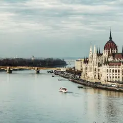 Budynek Parlamentu w Budapeszcie nad Dunajem. W tle most i panorama miasta. Pytanie: jaka jest waluta w Budapeszcie? Odpowiedź: Forint.