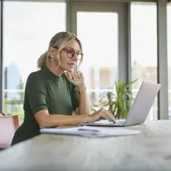 Kobieta w okularach pracuje na laptopie, szukając informacji, jak założyć konto w BIK.