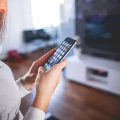 Kobieta trzyma telefon, szukając informacji, jak wyłączyć pakiet komfort Peako.