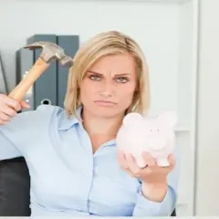 Zła mina kobiety z młotkiem i świnką-skarbonką. Chyba wie, kto nie płaci funduszu pracy.