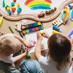 Dzieci tworzą kolorowe prace, jakby planowały, jak zdobyć dofinansowanie do przedszkola. Widać klocki, farby, kredki i papier.