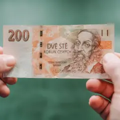 Dwieście koron czeskich, czyli jaka waluta jest w Czechach, trzymane w dłoniach.