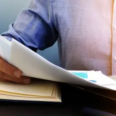 Mężczyzna przegląda dokumenty, zastanawiając się, czy można wyczyścić BIK. Obok leży otwarty notatnik i laptop.