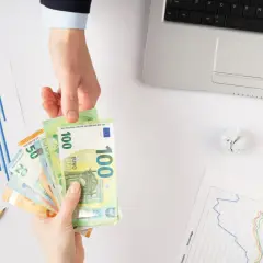 Ręce przekazują sobie euro. Obok leżą wykresy, kalkulator i monety. Zastanawiasz się, jaki podatek od pożyczki?