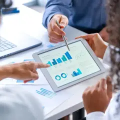 Analiza danych na tablecie, podobna do tego, co widzi bank w raporcie BIK: wykresy słupkowe, liniowe i kołowe.