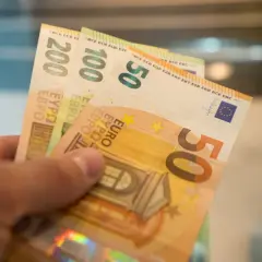 Dłoń trzyma banknoty 50, 100 i 200 euro. Od 2015 roku jaka waluta na Litwie to euro.