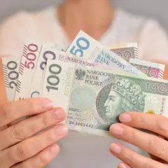 Dłonie trzymają polskie banknoty o nominałach 50, 100, 200 i 500 zł. Kto kontroluje fundusz socjalny w szkole?