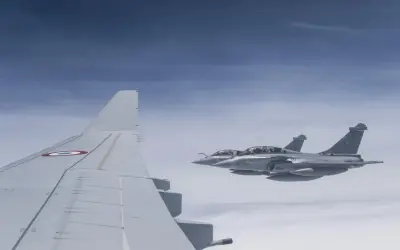 Dwa myśliwce Rafale, napędzane silnikami Safran, lecą w formacji nad chmurami. Widoczny fragment skrzydła samolotu z francuską kokardą.