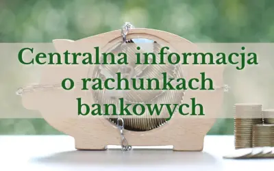 Drewniana skarbonka w kształcie świnki wypełniona monetami, z napisem "Centralna informacja o rachunkach bankowych".
