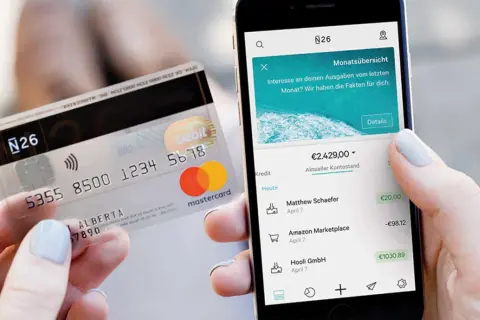 Karta N26 i smartfon z aplikacją bankową pokazującą saldo konta i ostatnie transakcje.