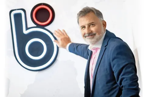 Mężczyzna w garniturze opiera się o logo, które może sugerować, kto wymyślił BLIK.