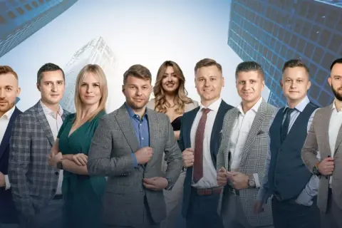 Grupa profesjonalistów w garniturach na tle nowoczesnych budynków.