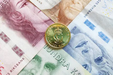 Szwedzka korona, czyli jaka waluta jest w Szwecji, widoczna na banknotach z portretami i złotej monecie z wizerunkiem króla Karola XVI Gustawa.