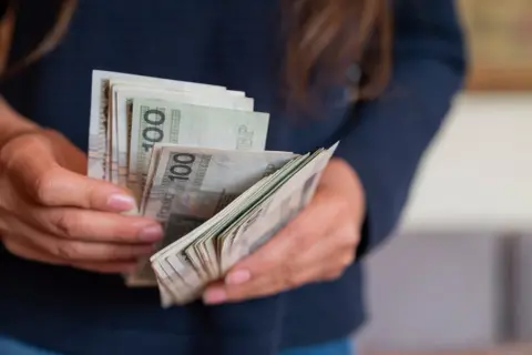 Dłonie trzymające plik banknotów 100 zł. Słowacja jaka waluta? Obecnie euro, ale kiedyś był to słowacki korona.
