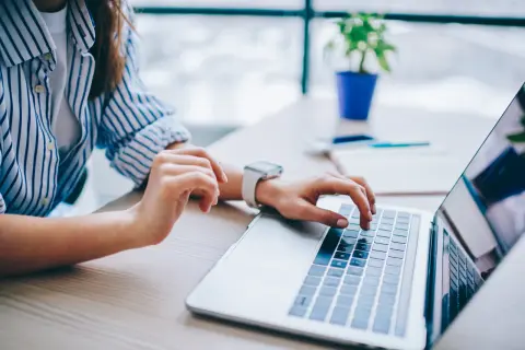 Kobieta pisze na laptopie, szukając informacji, jak anulować przelew mBank.