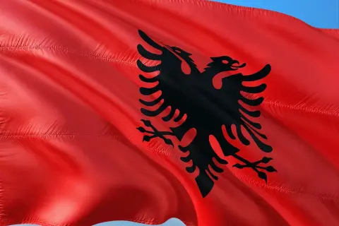Czerwona flaga Albanii z czarnym dwugłowym orłem. W Albanii obowiązuje waluta lek.