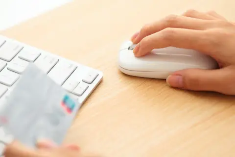 Dłoń trzyma kartę płatniczą przy klawiaturze, gotowa do transakcji online. Może to być początek procesu chargeback Santander.