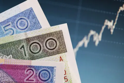 Polskie banknoty 20, 50, 100 zł na tle wykresu giełdowego. Dowiedz się, co to bankowy fundusz gwarancyjny.