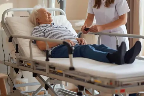 Starszy pan odpoczywa na łóżku rehabilitacyjnym. Dowiedz się, jakie jest dofinansowanie do łóżka rehabilitacyjnego, by zapewnić komfort bliskim.