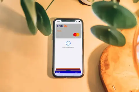Telefon z kartą ING i napisem "Hold Near Reader" pokazuje, jak płacić Apple Pay. Szybko i bezpiecznie.
