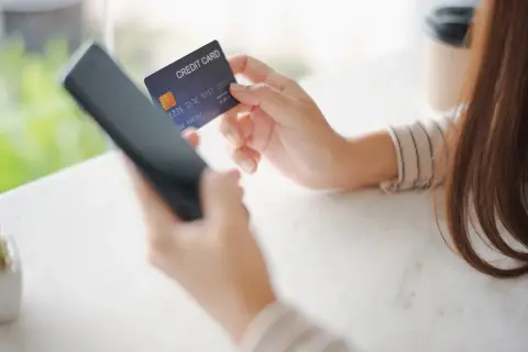 Kobieta używa telefonu i karty kredytowej, być może w celu zwrotu nierozliczonej transakcji Peako.