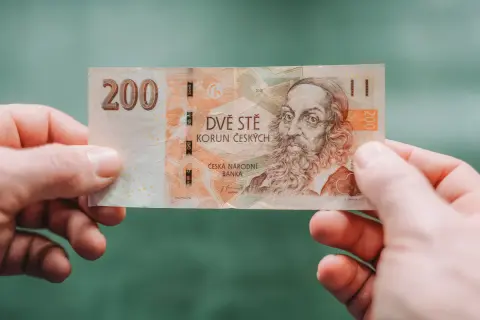 Dwieście koron czeskich, czyli jaka waluta jest w Czechach, trzymane w dłoniach.