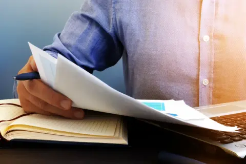 Mężczyzna przegląda dokumenty, zastanawiając się, czy można wyczyścić BIK. Obok leży otwarty notatnik i laptop.