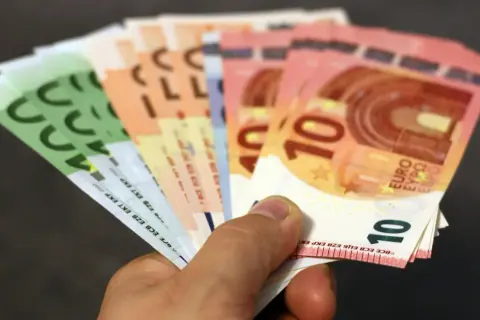 Dłoń trzyma banknoty euro. Choć w Bułgarii obowiązuje lew, euro jest powszechnie akceptowane w turystycznych miejscach.