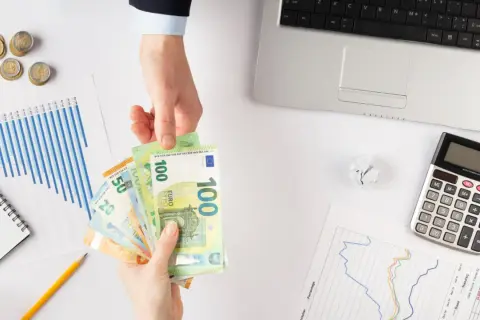 Ręce przekazują sobie euro. Obok leżą wykresy, kalkulator i monety. Zastanawiasz się, jaki podatek od pożyczki?