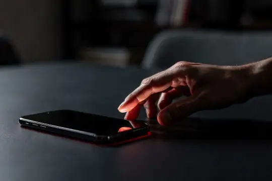 Dłoń dotyka ekranu telefonu, być może logując się do mBanku przez profil zaufany.