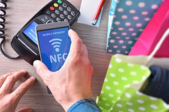 Płatność zbliżeniowa telefonem z użyciem NFC przy terminalu płatniczym.