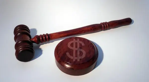 Młotek sędziowski i podstawa z symbolem dolara. Jak uniknąć kary od ubezpieczeniowego funduszu gwarancyjnego?