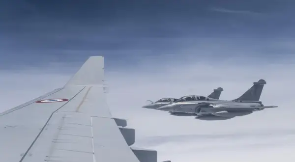 Dwa myśliwce Rafale, napędzane silnikami Safran, lecą w formacji nad chmurami. Widoczny fragment skrzydła samolotu z francuską kokardą.