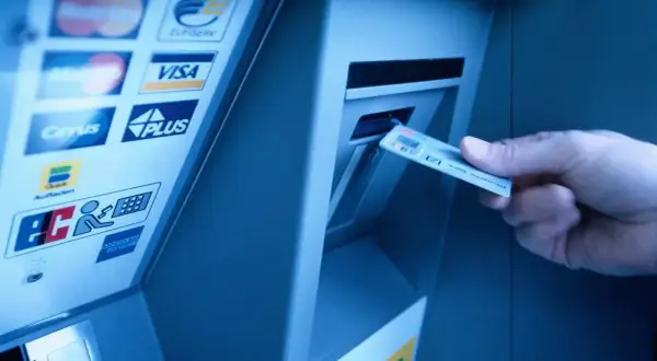 Wpłatomat mBank: ręka wkłada kartę do wpłatomatu. Sprawdź, ile można wpłacić do wpłatomatu mbank.