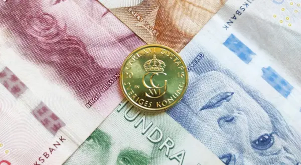 Szwedzka korona, czyli jaka waluta jest w Szwecji, widoczna na banknotach z portretami i złotej monecie z wizerunkiem króla Karola XVI Gustawa.