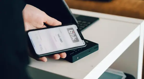 Dłoń trzyma smartfon z aplikacją Blik. Dowiedz się, jak zmienić limit Blik w Millenium, by bezpiecznie zarządzać finansami.
