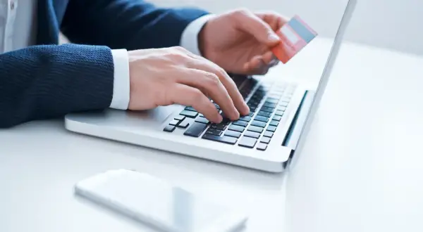 Mężczyzna wpisuje dane karty Millenium na laptopie, przygotowując się do aktywacji.