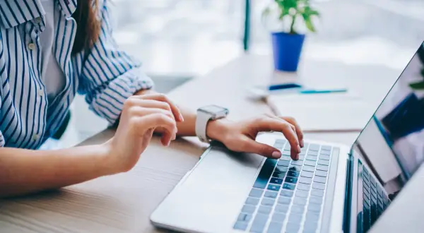 Kobieta pisze na laptopie, szukając informacji, jak anulować przelew mBank.