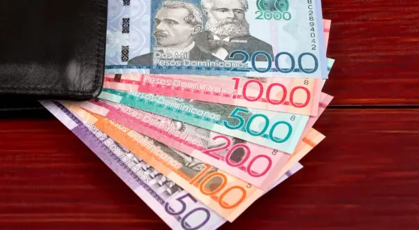 Dominikańskie pesos w różnych nominałach wychodzące z czarnego portfela.