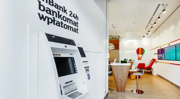Wpłatomat mBank 24h, gotowy do obsługi o każdej porze. Wnętrze banku z nowoczesnym wystrojem.