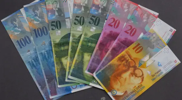 Różne banknoty CHF, czyli franków szwajcarskich, leżą na ciemnym tle. Widać nominały 10, 20, 50 i 100.