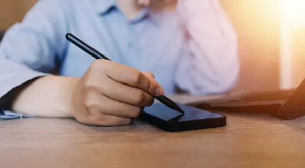 Osoba korzysta ze smartfona i rysika, szukając informacji, jak zmienić numer telefonu w mBank.